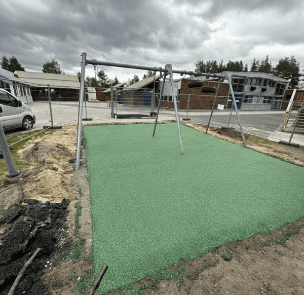 Nauja žalios spalvos guminė danga įrengta po sūpynėmis vaikų žaidimų aikštelėje, teritorija aptverta statybine tvora