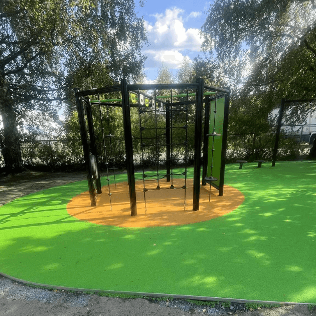 Užbaigta vaikų žaidimų aikštelė su liejama spalvota EPDM gumos danga ir laipiojimo įrenginiu.