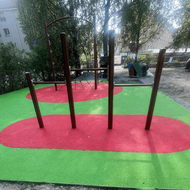Užbaigta vaikų žaidimų aikštelė su spalvota liejama EPDM gumos danga ir įrengtais laipiojimo elementais.
